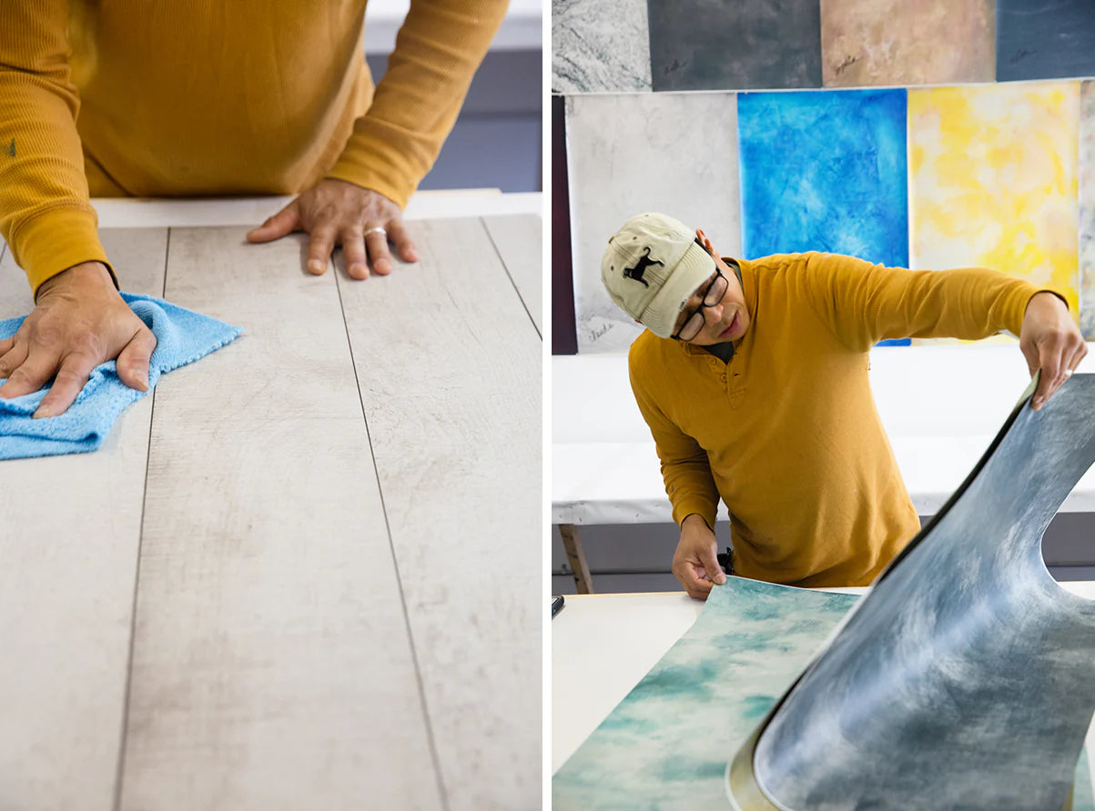 Joe, co-owner of Poppy Bee, is cleaning a surface with a cloth and arranging artwork on a table.