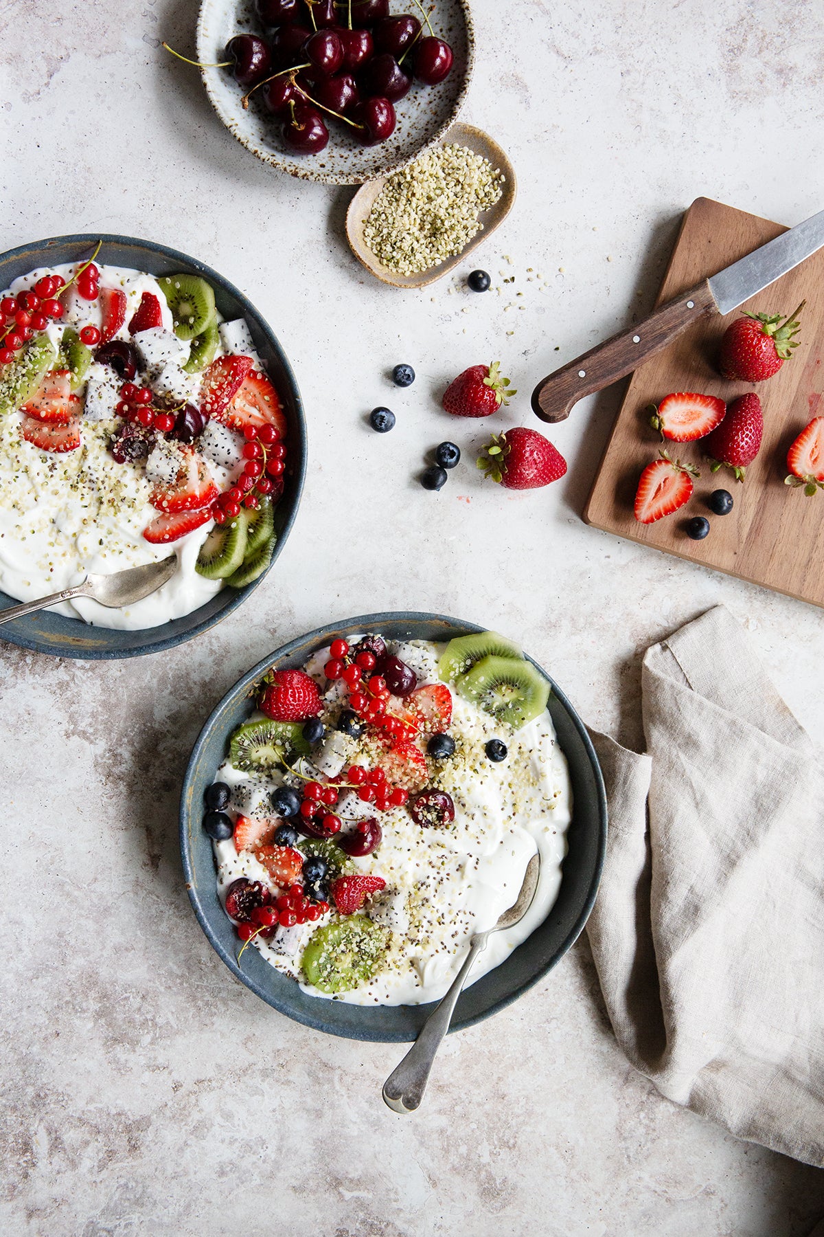 Yogurt, cherries, and other fruits featured on a granite textured photography backdrop.