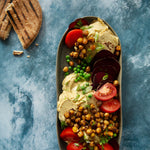 Axel Food Photography Background with platter of hummus, tomatoes, chickpeas and pita bread
