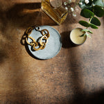 Dark and moody stone photography surface with perfume, jewelry and plants with dramatic shadows
