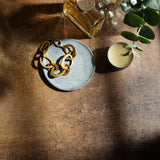 Dark and moody stone photography surface with perfume, jewelry and plants with dramatic shadows