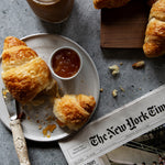 Rustic gray stone photography surface with croissants, iced coffee and newspaper