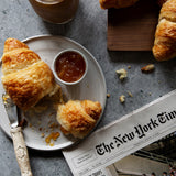 Rustic gray stone photography surface with croissants, iced coffee and newspaper