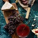 Dramatic green stone photography surface with cheese, salami and fruit