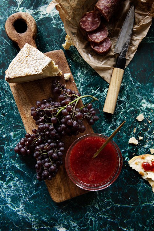 Dramatic green stone photography surface with cheese, salami and fruit