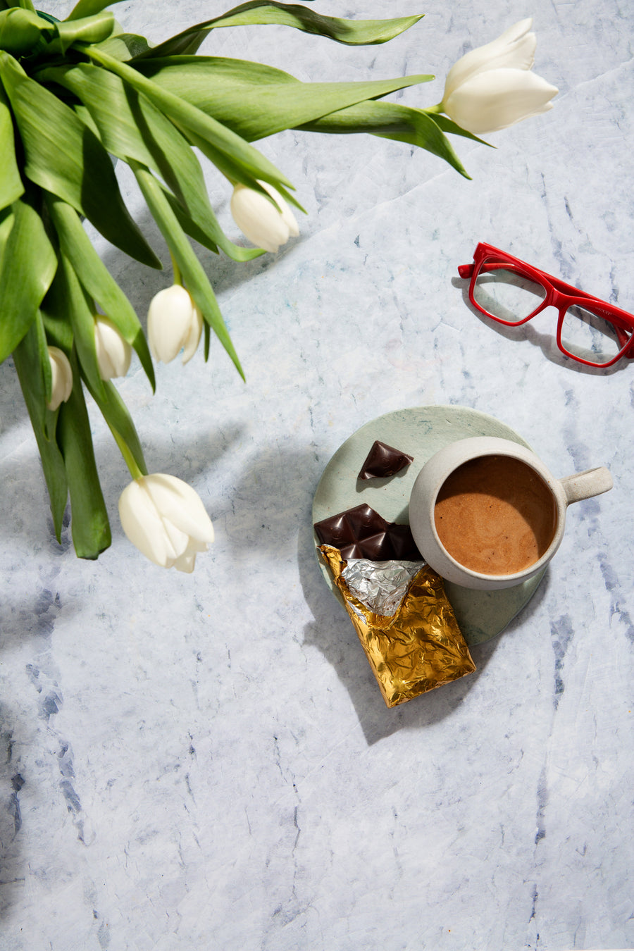 Light blue stone photography surface with tulips, coffee and chocolate