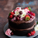 Dark metal photography surface with chocolate cake topped with fruit and flowers