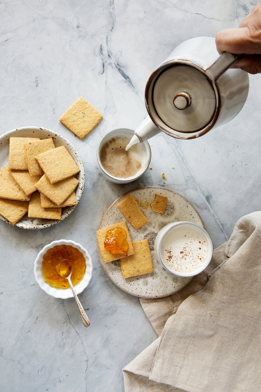Light and airy marble photography surface with crackers, marmalade and tea