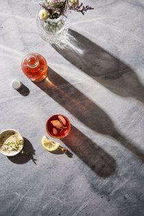 Birch Food Photography Background with vase of flowers, bottle of red liquid, glass of juice and slice of lemon