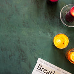 Dark green stone photography surface with candles and wellness magazine