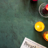 Dark green stone photography surface with candles and wellness magazine