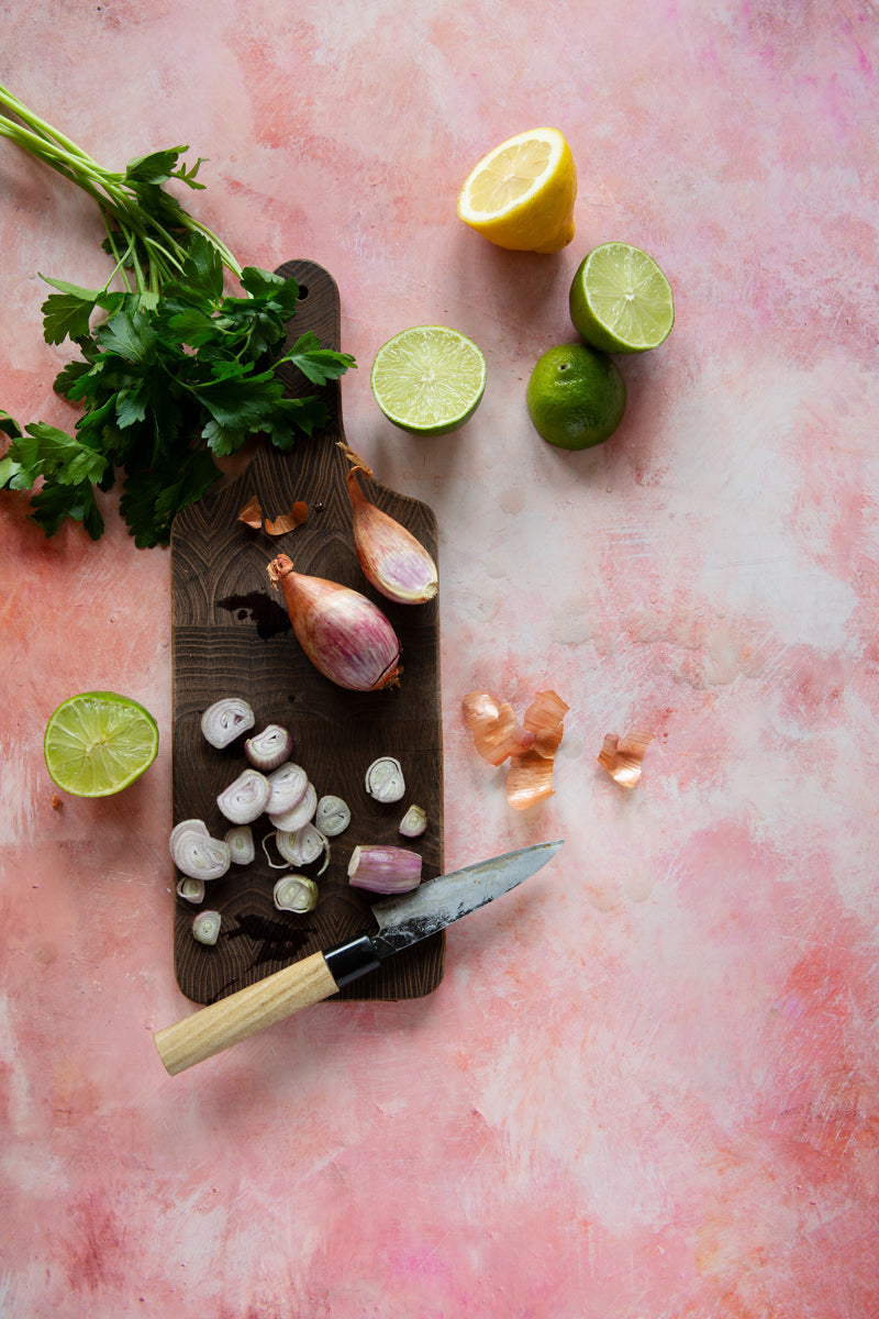 Pink painted photography surface with shallots, herbs and limes